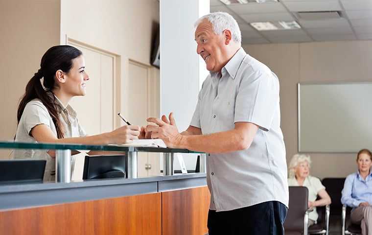 patient talking to front desk worker in clinic